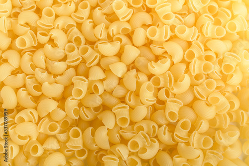 Heap of dried cornetti rigati traditional Italian pasta on a plate ready to be cooked, isolated on a white table, top view or flat lay of healthy food 