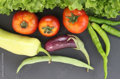 Vegitables on a black background (tomatos, escarole leaves, brinjal or egg plant, chillis, capcicum banana pepper closeup shot with copy space