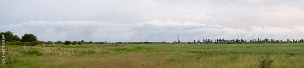 Cloudy landscape, village before the rain, visible large cumulus clouds and clouds over the village.