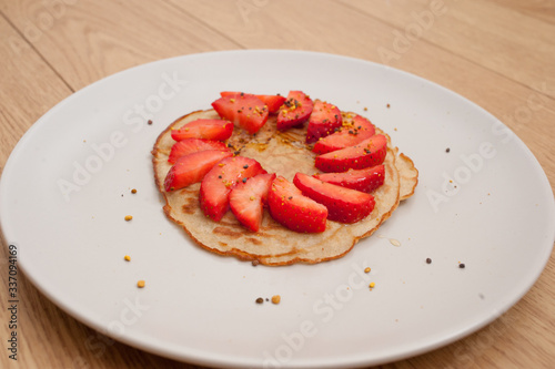strawberry pancake on a white plate in a wooden table