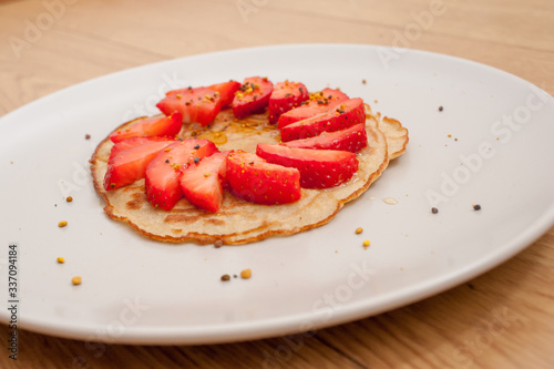 strawberry pancake on a white plate in a wooden table