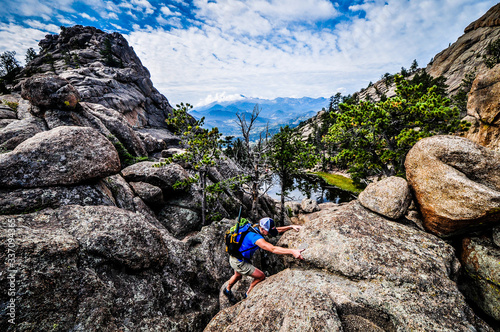 man scrambling on rock cliff