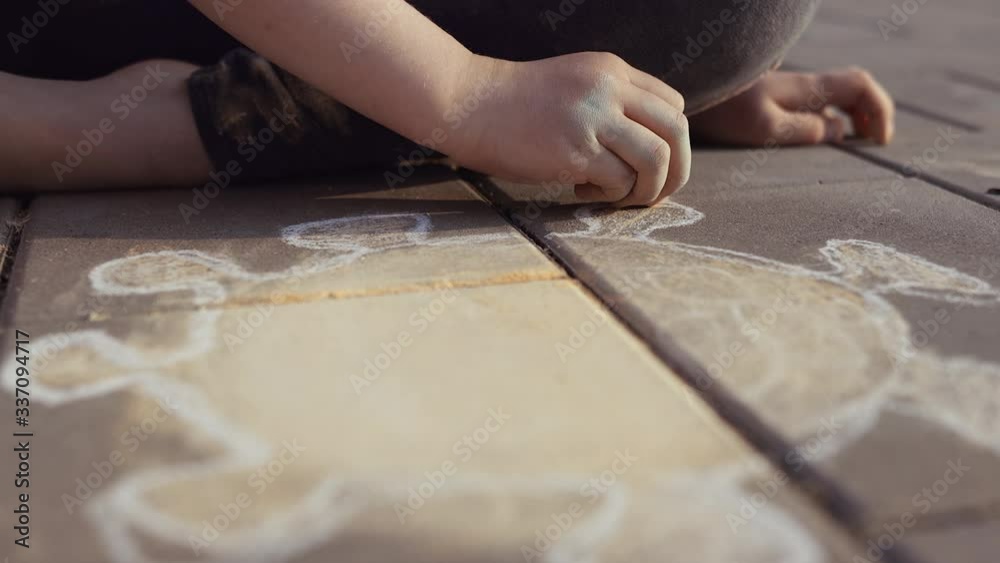 4K. Dirty girl draws silhouette of a corona virus with a chalk on a pavement. Poor sad little child - Stay home and self isolation in quarantine concept.