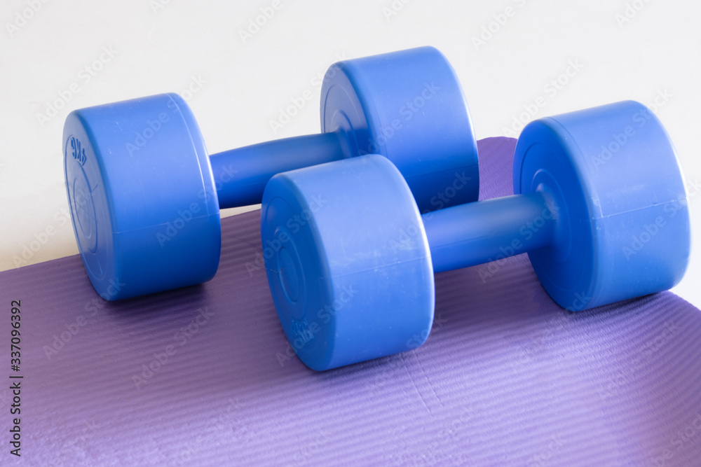 sports ware for gym. Sport concept. Sporting items on purple background or lavender. blue dumbbell on purple mat sport. Space for your text. Sports concept. Sport equipment. Fitness sports ware for gym. Sport concept. Sporting items on purple background or lavender. blue dumbbell on purple mat sport. Space for your text. Sports concept. Sport equipment. Fitness