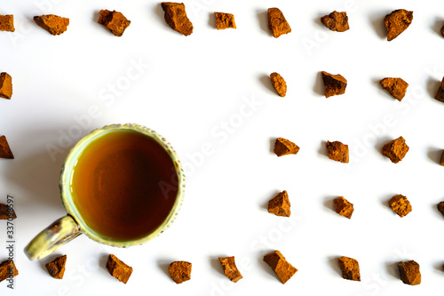 chaga mushroom and cup of tea. broken pieces of birch tree chaga mushroom and for brewing natural medicinal antitumor and antiviral detox tea, isolation on white background. regular pattern photo