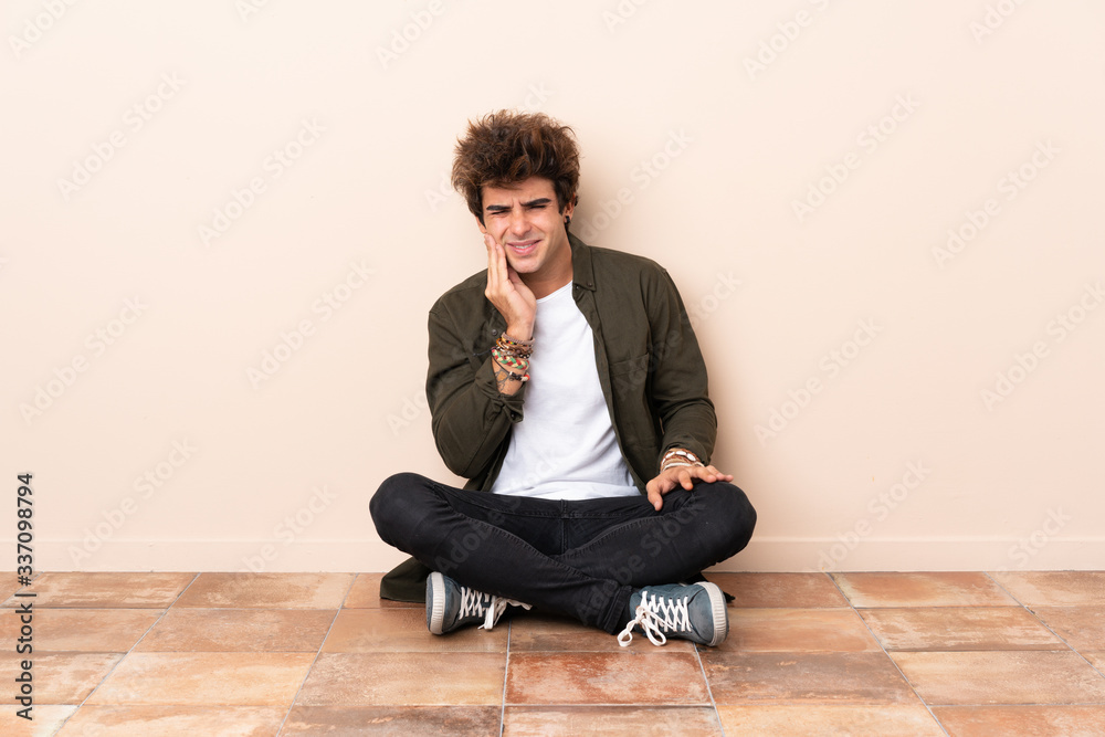 Young caucasian man sitting on the floor with toothache Young caucasian man sitting on the floor with toothache