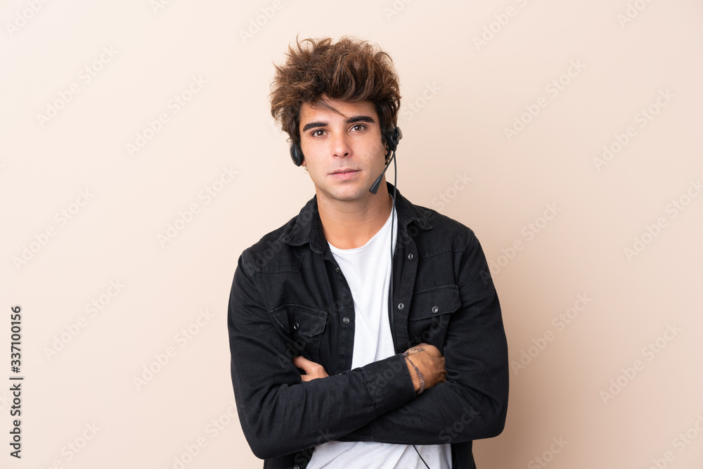 Telemarketer man working with a headset over isolated background keeping arms crossed Telemarketer man working with a headset over isolated background keeping arms crossed