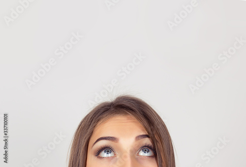 cropped image half face eyes of woman looking up white grey wall