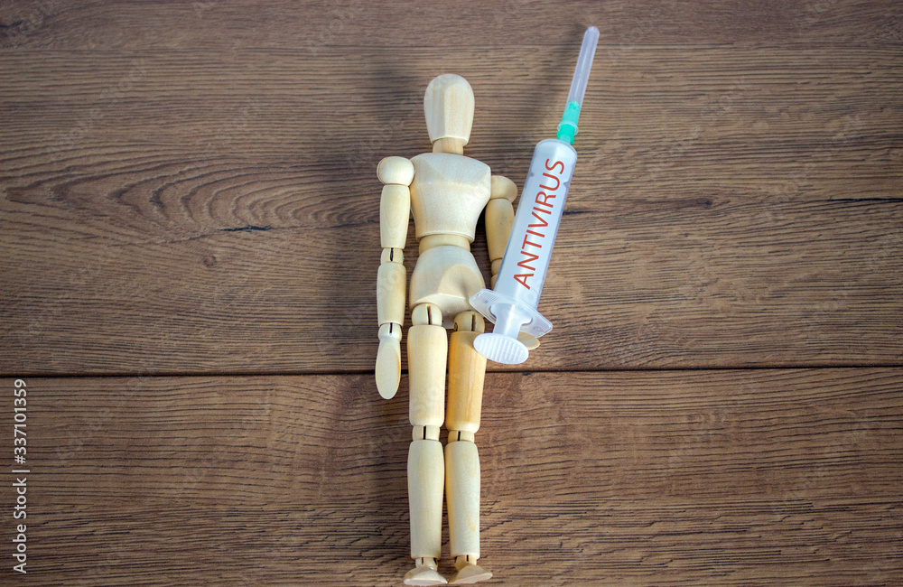 COVID-19 Pandemic Coronavirus concept. Wooden model of a man holding a syringe labeled antivirus. COVID-19 Pandemic Coronavirus concept. Wooden model of a man holding a syringe labeled antivirus.