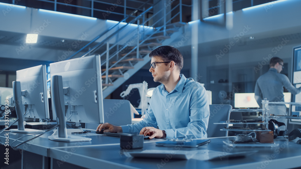 Electronics Development Engineer Sitting at His Desk Uses personal Computer for Programming. Team of Professionals Use Digital Whiteboard with CAD Software for the Modern Industrial Engineering Design