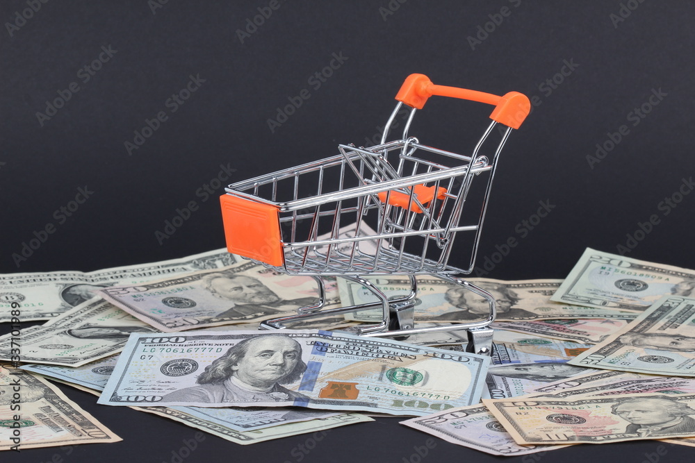 Shopping cart with dollars inside isolated on black