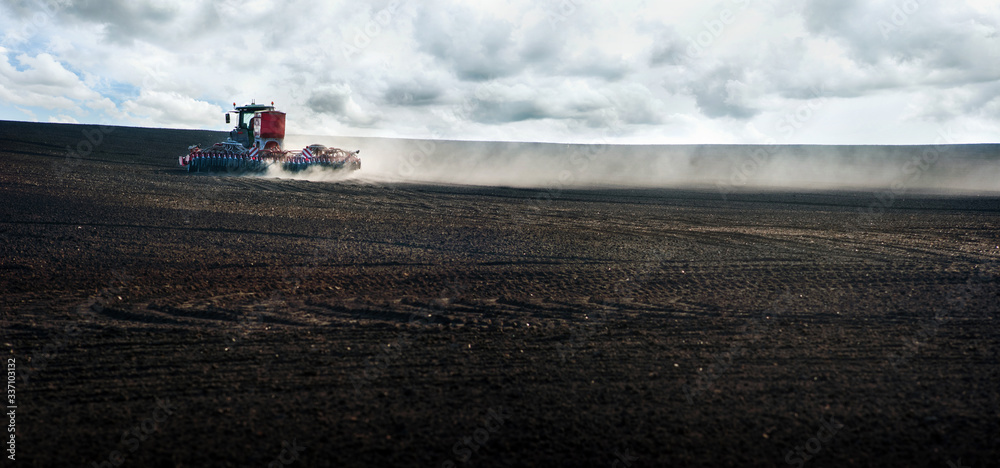 Fototapeta Panoramic view, tractor work plow the field with durst . Agricultural works for processing, tillage. Farmers preparing the land and fertilizing. Farmland, tractor with seeder, sowing and fertilizer