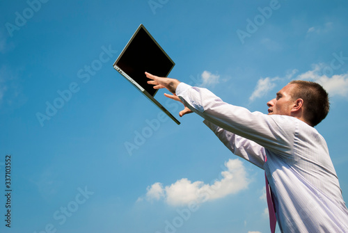 Office worker reaching up to type on a mobile laptop floating outdoors in sunny blue sky