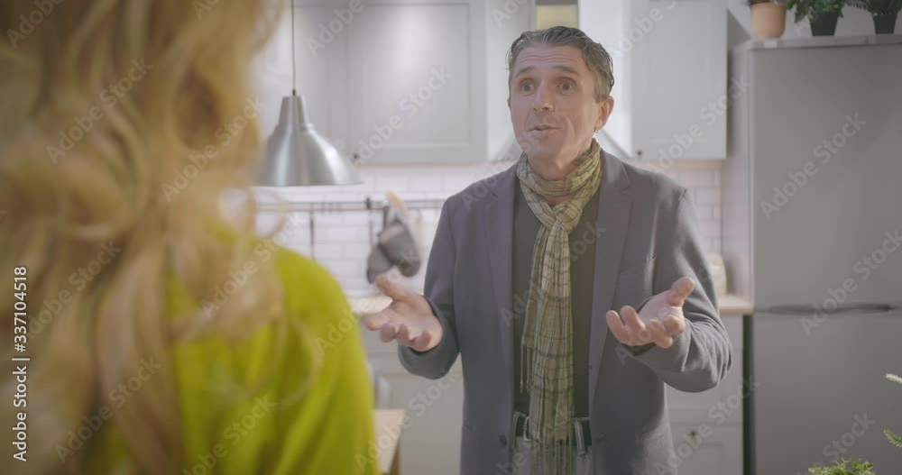 Middle-aged couple chatting in kitchen in evening Middle-aged couple chatting in kitchen in evening