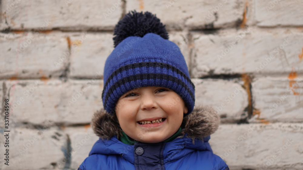 Portrait of little cute boy in a blue knitted hat with pompom Portrait of little cute boy in a blue knitted hat with pompom