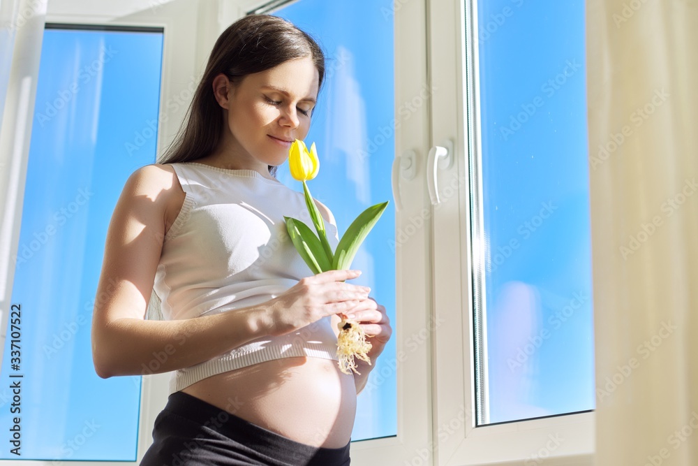 Portrait of pregnant woman with one yellow tulip flower Portrait of pregnant woman with one yellow tulip flower