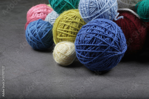 A lot of multi-colored yarn balls on the dark background. Knitting yarn close-up. Knitting is needlework and creativity. Copy space.