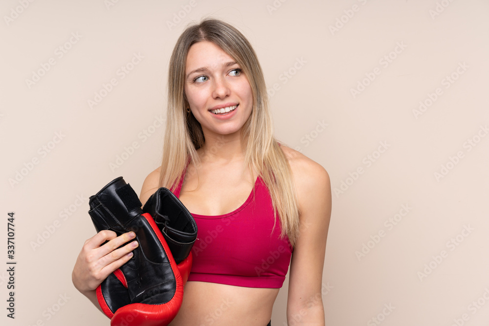 Young sport blonde woman over isolated background with boxing gloves