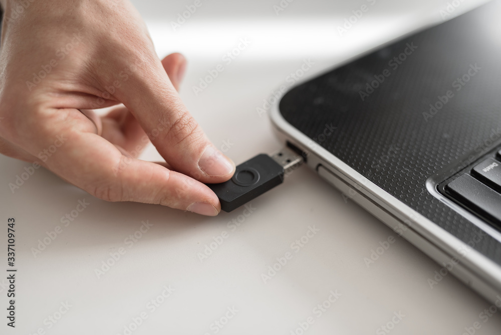 a man plugs a USB flash drive into a laptop with his hand a man plugs a USB flash drive into a laptop with his hand