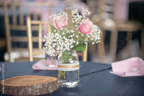 Romantic pink roses and babies breath flowers table centerpiece in glass mason jar with lace decoration