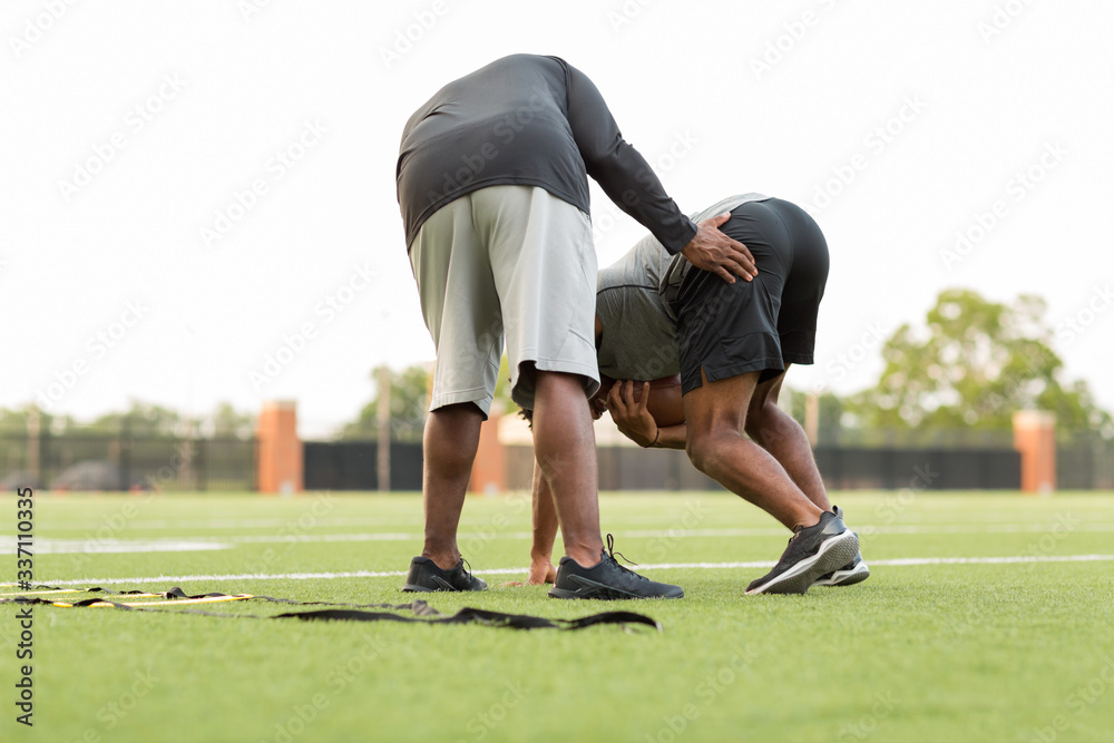 American Football coach training a young athlete. American Football coach training a young athlete.