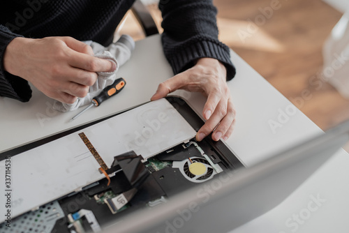 A man disassembles a laptop. Removes the keyboard. Computer service and repair concept. Laptop disassembling in repair shop, close-up. Electronic development, technology fixing