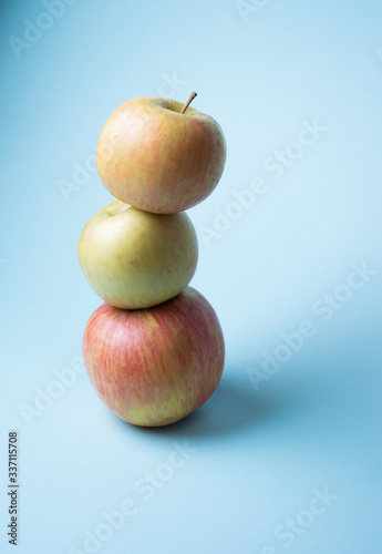 tower from yellow and red apples on cold blue background