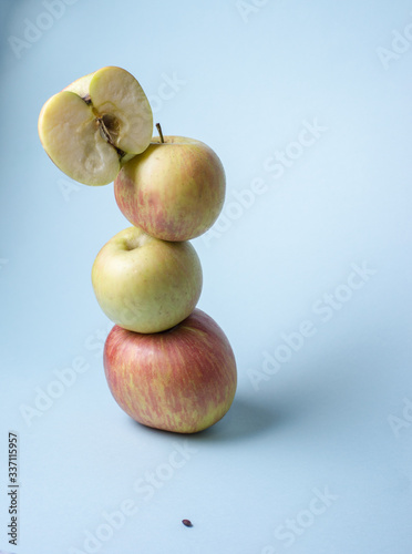 tower from yellow and red apples on cold blue background
