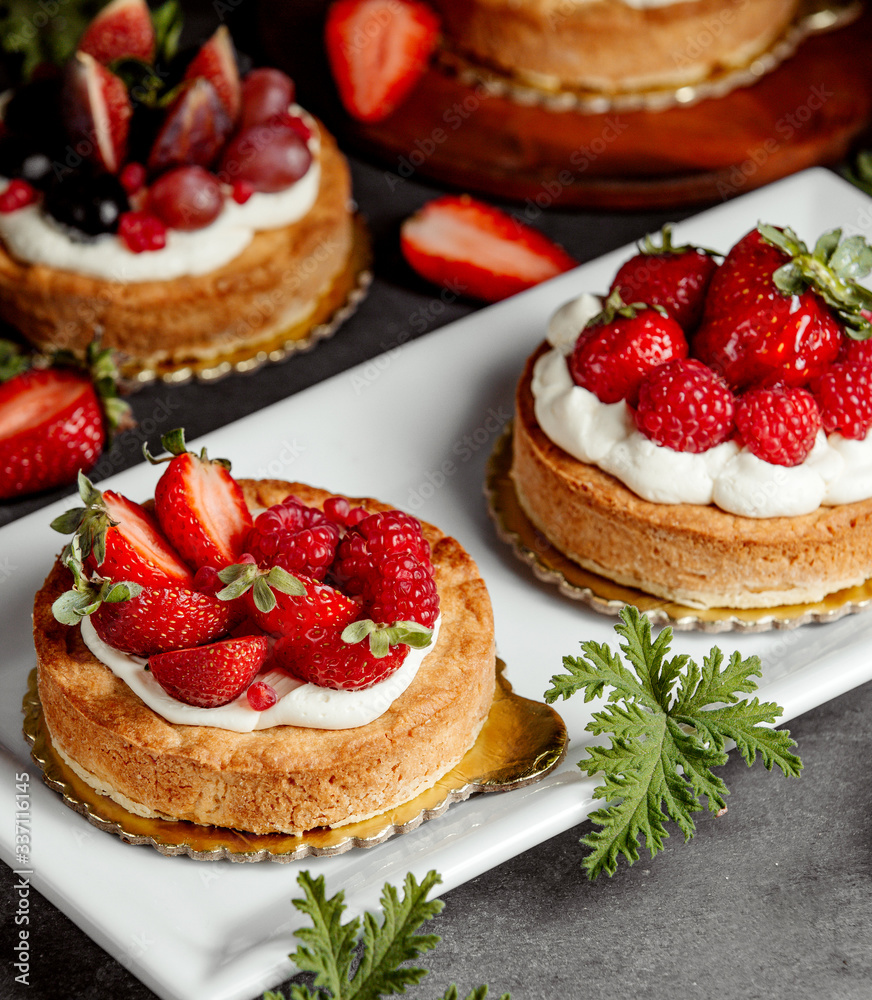 two small pies decorated with cream strawberry and raspberries two small pies decorated with cream strawberry and raspberries