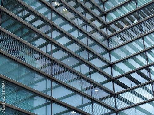 a full frame modern office architecture abstract with angular steel geometric shapes and buildings reflected in blue glass windows