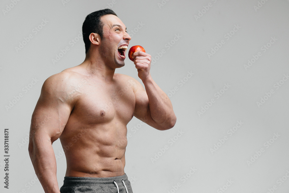 Sporty sexy guy eating fruit on a white background. Diet. Healthy diet Sporty sexy guy eating fruit on a white background. Diet. Healthy diet
