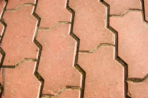 Texture of a footpath paved with red brick paving slabs.