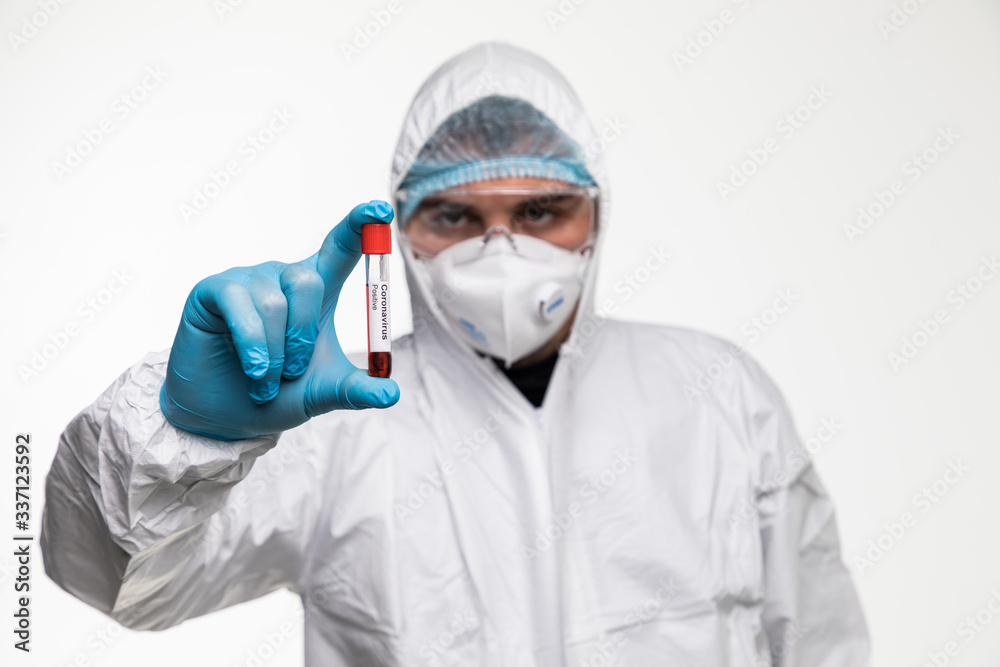 Laboratory technician man hand hold on positive blood sample tube for corona virus test , COVID-19. Scientist with blue gloves and mask for protection. Vaccine research for the 2019-nCoV Laboratory technician man hand hold on positive blood sample tube for corona virus test , COVID-19. Scientist with blue gloves and mask for protection. Vaccine research for the 2019-nCoV