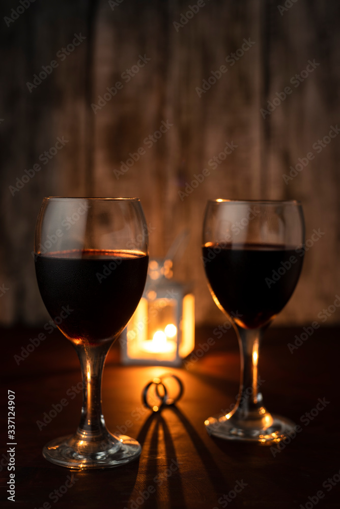 dos copas de vino celebrando con dos anillos en una mesa calida a la luz de  la vela Stock Photo | Adobe Stock