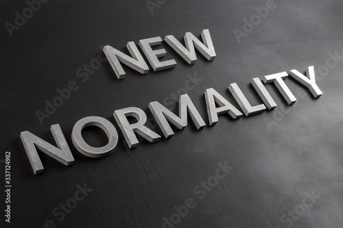 the words new normality laid with silver metal letters on flat black matte surface in slanted diagonal perspective photo