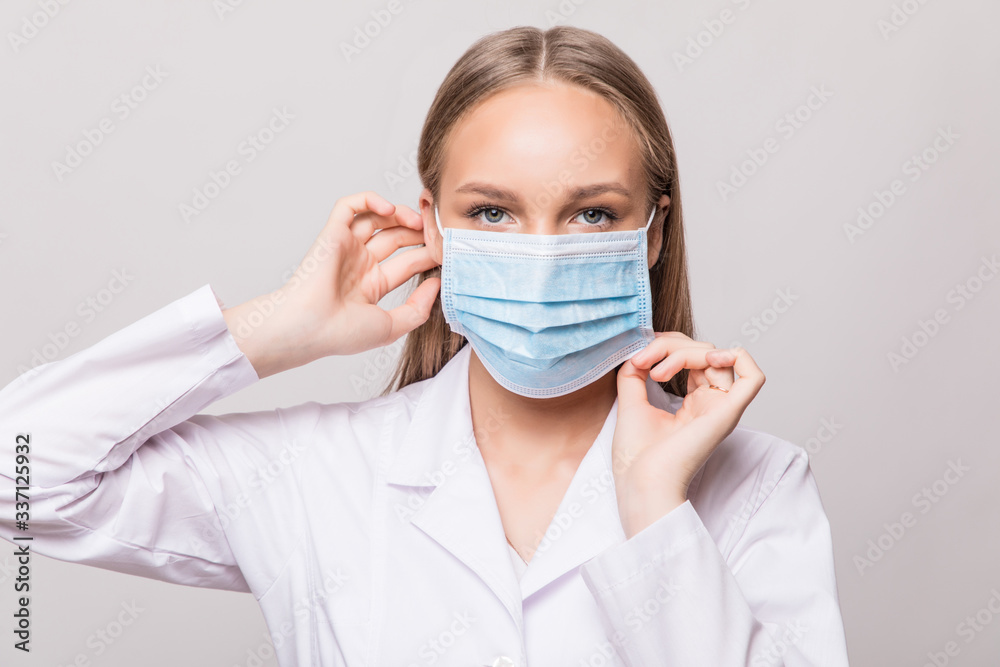 Portrait of a female surgeon putting on a mask over grey background Portrait of a female surgeon putting on a mask over grey background