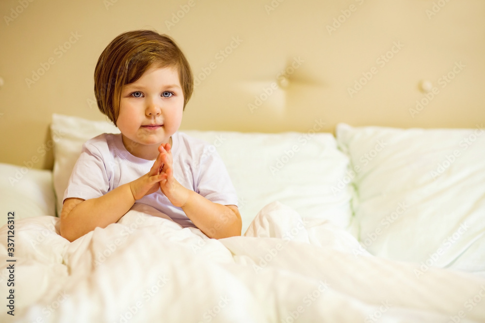 a sweet little girl with blue eyes ,lying in a white bed, under quarantine because of the covid-19 pandemic a sweet little girl with blue eyes ,lying in a white bed, under quarantine because of the covid-19 pandemic
