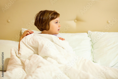 a sweet little girl with blue eyes ,lying in a white bed, under quarantine because of the covid-19 pandemic