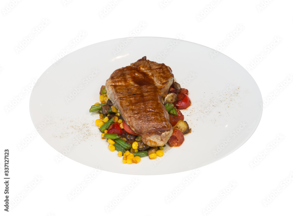 A piece of grilled pork with vegetables on a white plate. Blurred pink background