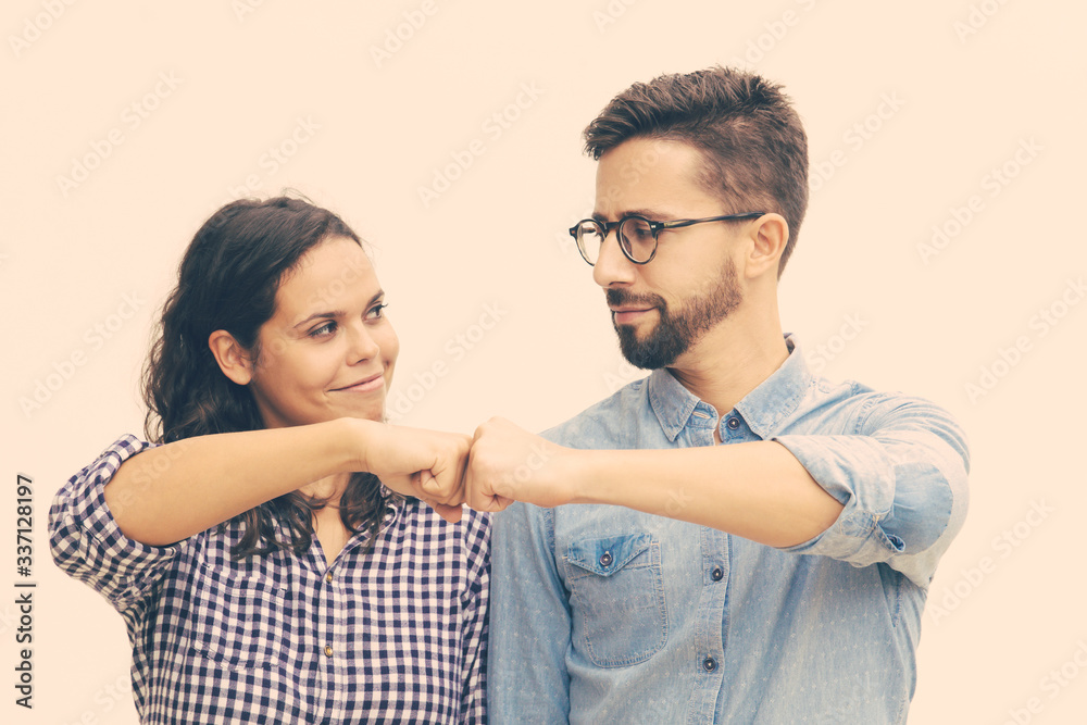 Satisfied couple making fist bump gesture. Young woman in casual and man in glasses standing isolated over white background. Cooperation concept Satisfied couple making fist bump gesture. Young woman in casual and man in glasses standing isolated over white background. Cooperation concept