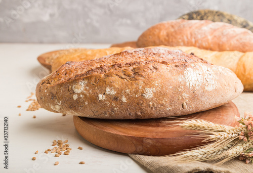 Different kinds of fresh baked bread on a white wooden background. side view, selective focus.