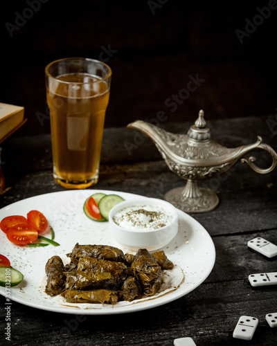 a plate of grape leaves dolma served with yogurt cucumber and tomato