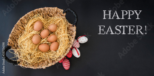 Happy Easter greeting card. Red Easter eggs and natural eggs in basket on black background