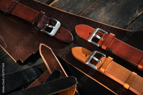 Handmade watch straps on wooden rustic surface. Different leather colour tones. Closeup.