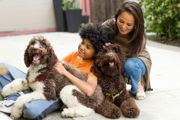 Mother and her son laughing and playing with their dog.