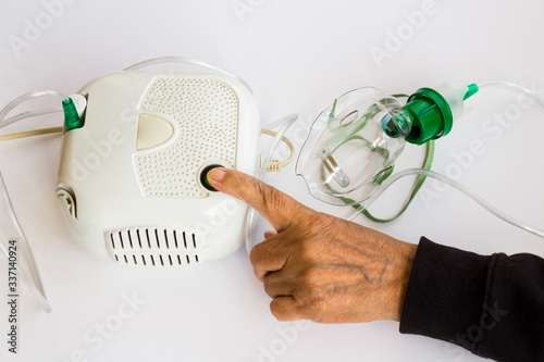Φωτογραφία Home type mini air machine with oxygen mask on hand touches on-off button of older person