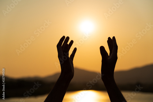 Closeup woman hands praying for blessing from god during sunset background. Hope concept. photo