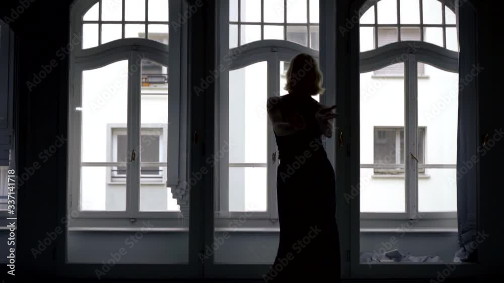 The silhouette of a girl in a long skirt , she is in a dark large room with large Windows and dances beautifully. Makes movements with his hands, turns around. The silhouette of a girl in a long skirt , she is in a dark large room with large Windows and dances beautifully. Makes movements with his hands, turns around.