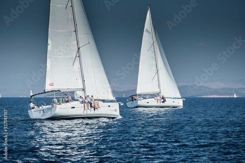 The race of sailboats, a sail regatta, reflection of sails on water, Intense competition, number of boat is on aft boats, Bright colors, island is on background