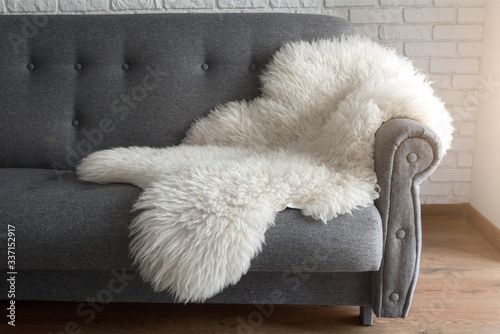 White sheep skin on a gray sofa. A cozy place to relax in the apartment